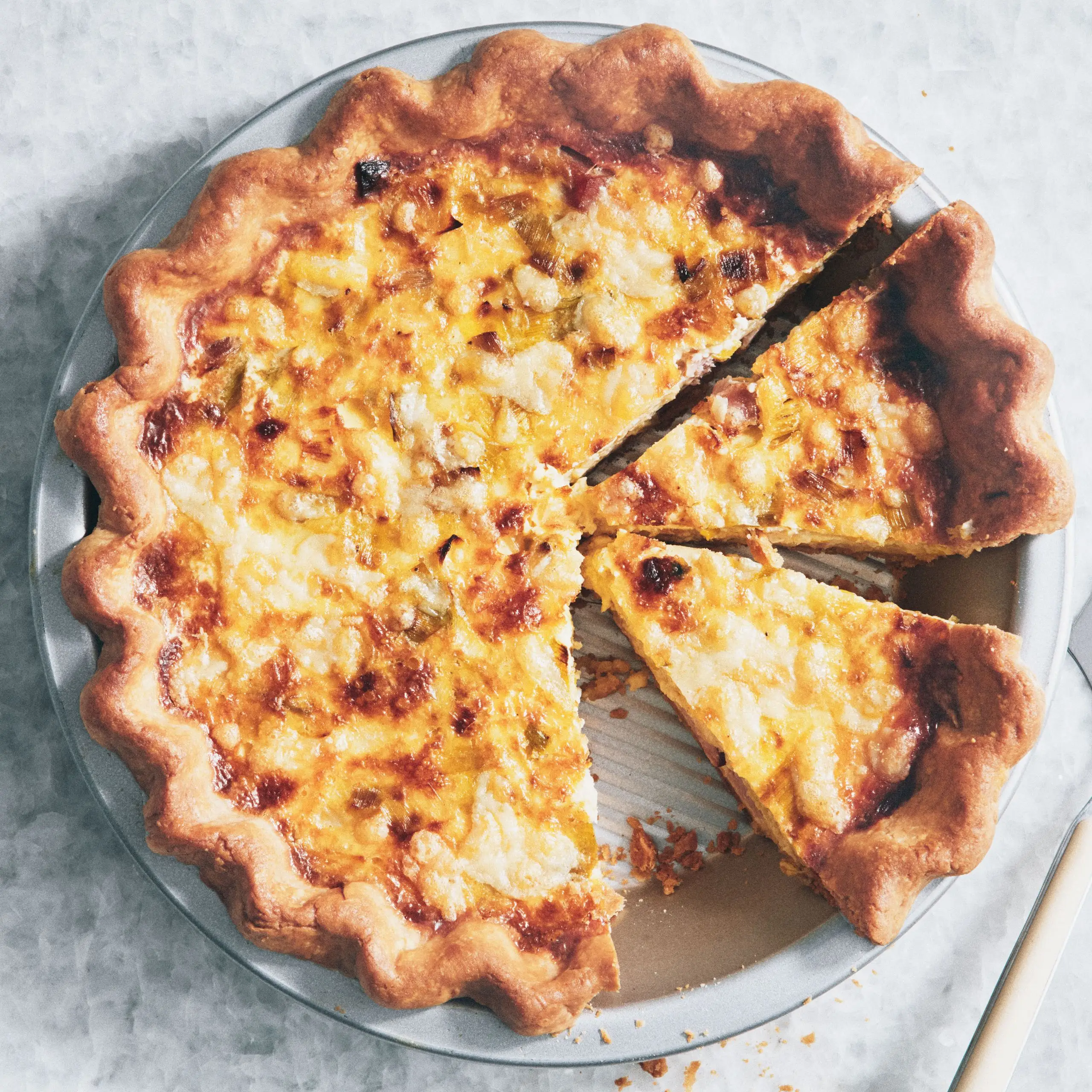 Overhead view of a ham and cheese quiche sliced into wedges.