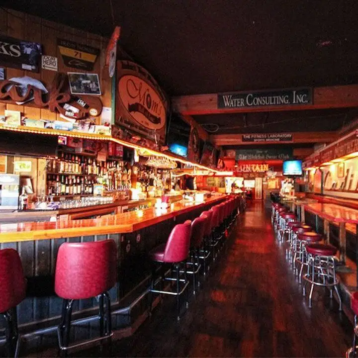 the great northern bar in montana. red sturdy backed stool and backless red stools both run down two wood bar tops
