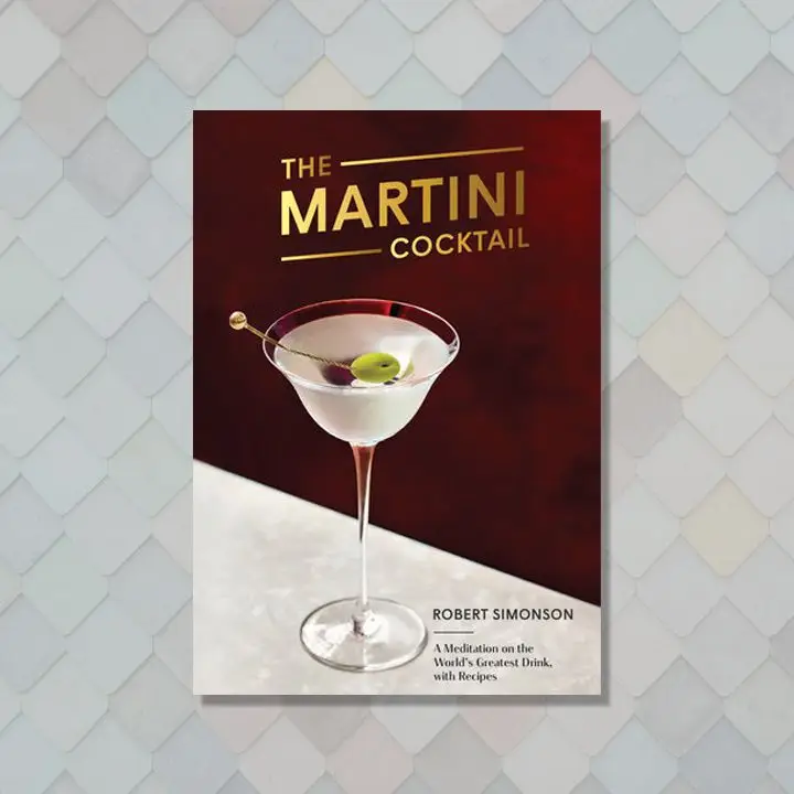 The Martini Cocktail cover with gold sans serif title text, a martini in a fine stemmed glass with an olive on a metal pick sitting atop a white countertop against a burgundy background