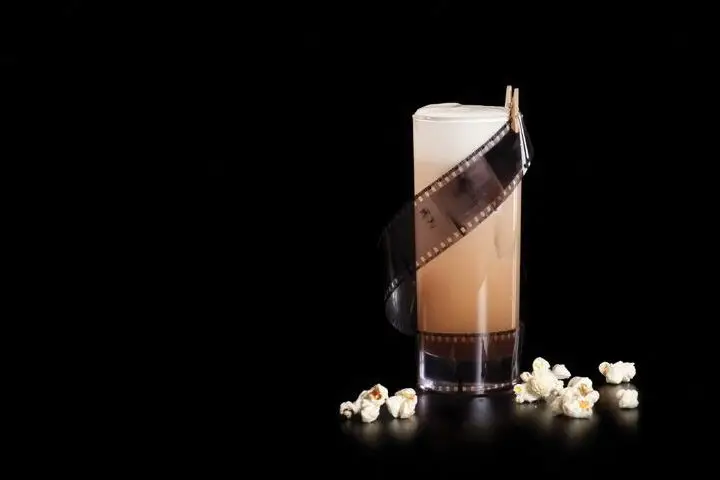 Trillby & Chadwick Detectives Agency cocktail with roll of film garnish and popcorn scattered around it
