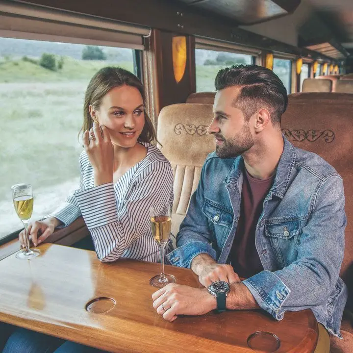 Jose Cuervo Express Train. A woman and a man are holding flutes and the vistas of tequila country are visible out their train-seat window
