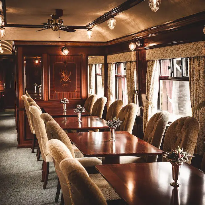 Scotch Malt Whisky Tour Train. the inside of a train car shows tufted dining chairs and dark-wood tables