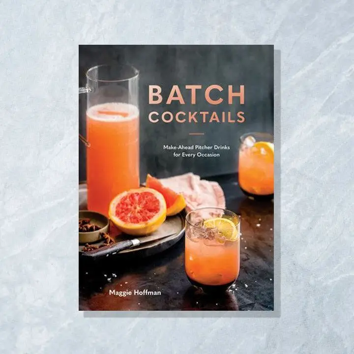 Batch Cocktails cover featuring a tall glass pitcher and two rocks glasses filled with a pink-orange colored cocktail along with sliced citrus and and spices scattered around