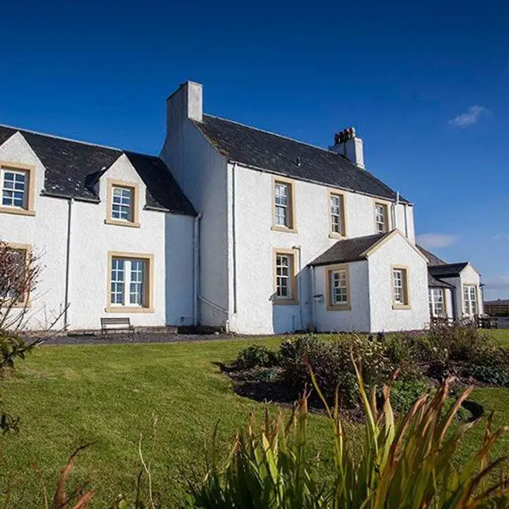 Glenegedale House, the building has a whitewashed exterior and blond trim around the windows