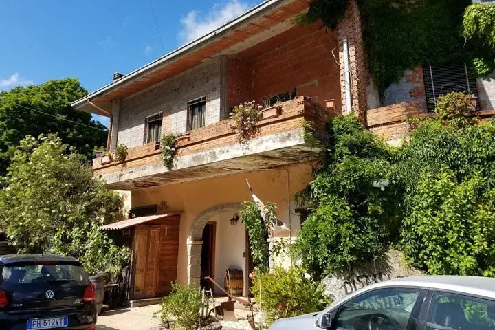 A two-story Italian home partially covered by greenery