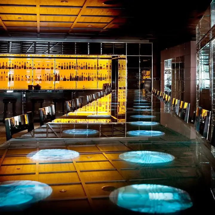 Bar Centro interior, with yellow backlit bottle collection and a long communal table