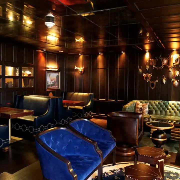Library Bar interior with a bright blue upholstered pair of love seats and dark wood paneled walls
