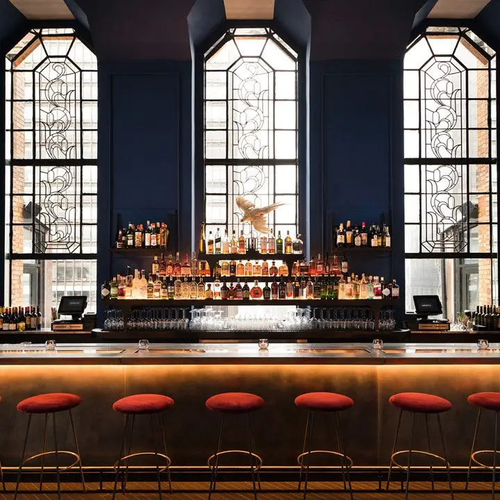 Ophelia interior with view of bar and floor-to-ceiling stained glass windows behind the bar itself