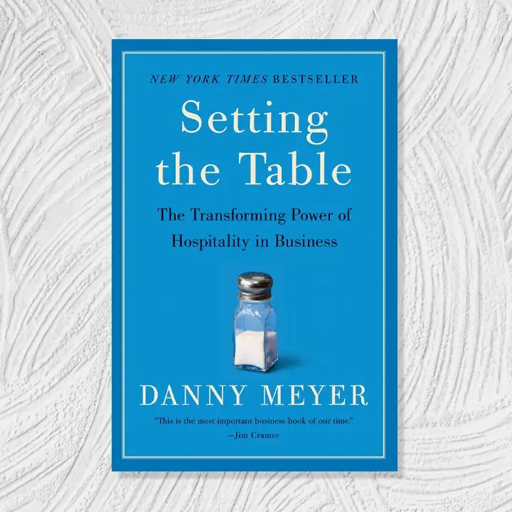 Setting the Table cover, light and dark blue background with black and white serif text around a small image of a salt shaker