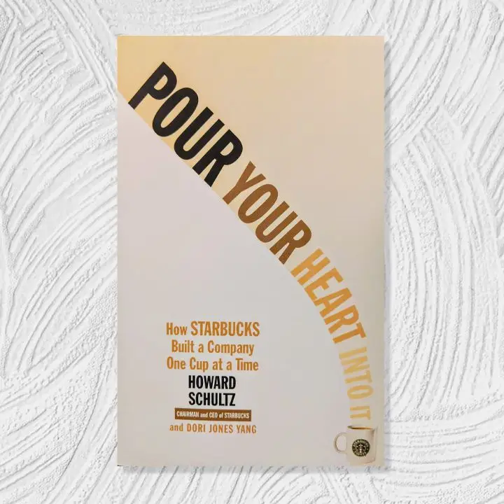 Pour Your Heart Into It cover, coffee-colored gradient background and text with a curved vertical title leading into a Starbucks mug