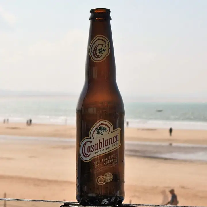 a bottle of Casablanca beer with the beach and coast in the background
