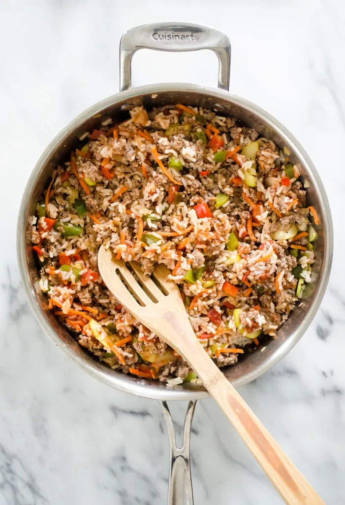 All of the ingredients for the filling part of the easy stuffed pepper casserole in a large skillet with a wooden spoon. ' title='Easy Stuffed Pepper Casserole