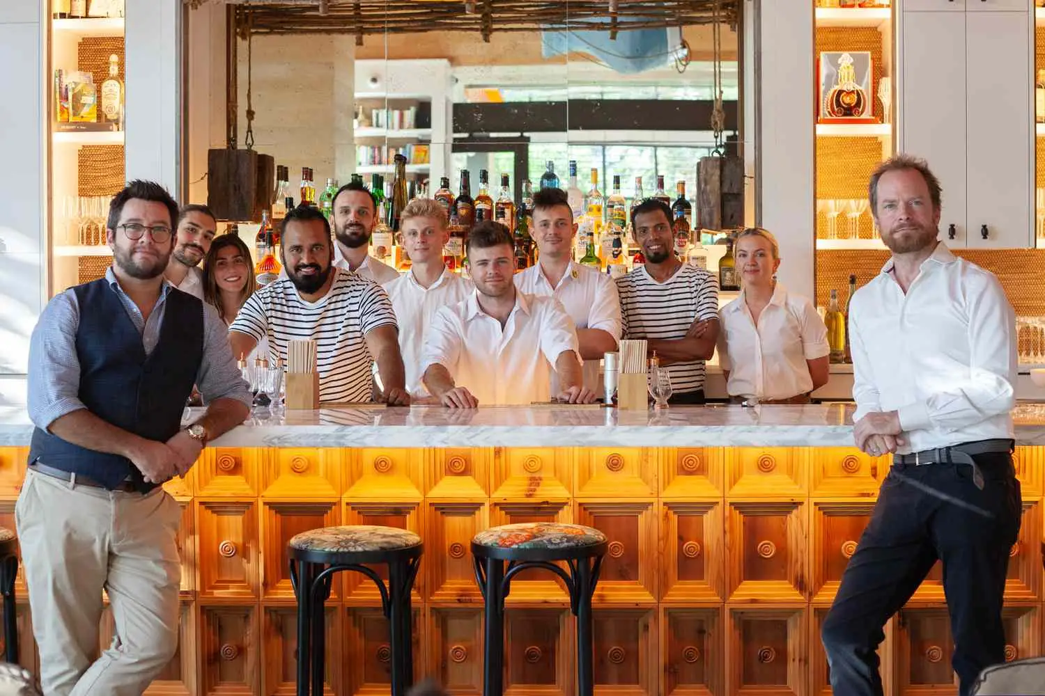 Andrew Copsey and Jim Wrigley standing on either sides of the bar at Library By The Sea, with the staff behind the bar in-between them