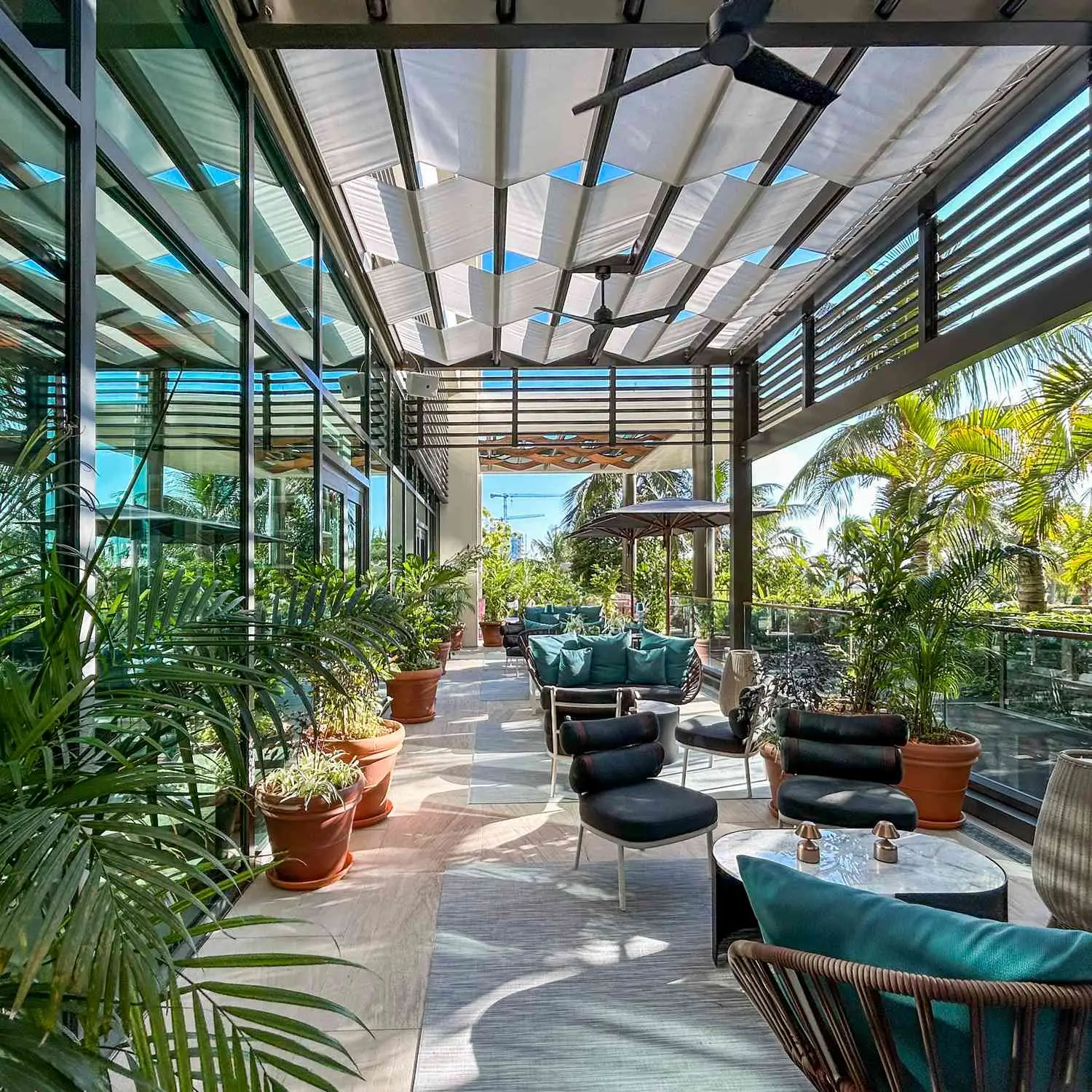 Exterior of Library By The Sea, patio showing wicker chairs, tables, and palm trees
