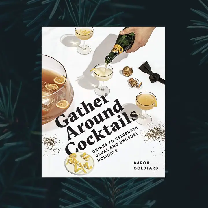 Gather Around Cocktails cover featuring a white background with scattered gold glitter, a punch bowl, a plate of lemon twists, a bow tie, a Champagne cork and cage, and three coupe glasses