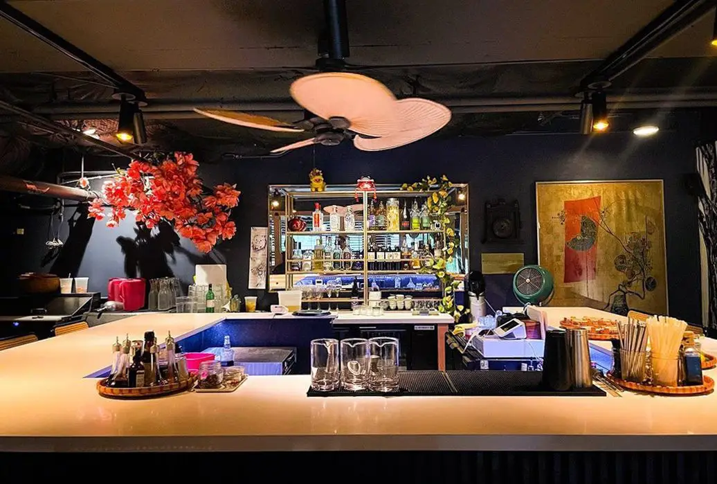 Interior bar of Phocific Standard Time, with array of mixing glasses, paddle fan, plants and ingredients