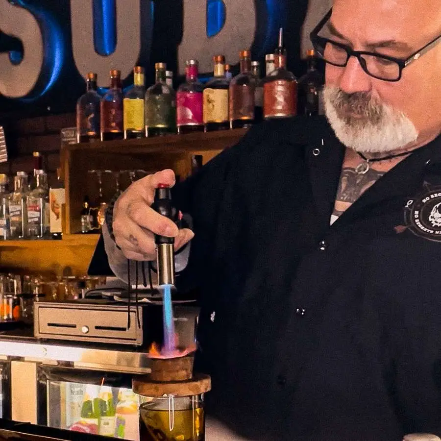 Jeff Gustin of Inmoxicated Dry Bar & Bottle Shop in Racine, Wisconsin holding a blowtorch over a cocktail in his non-alcoholic bar