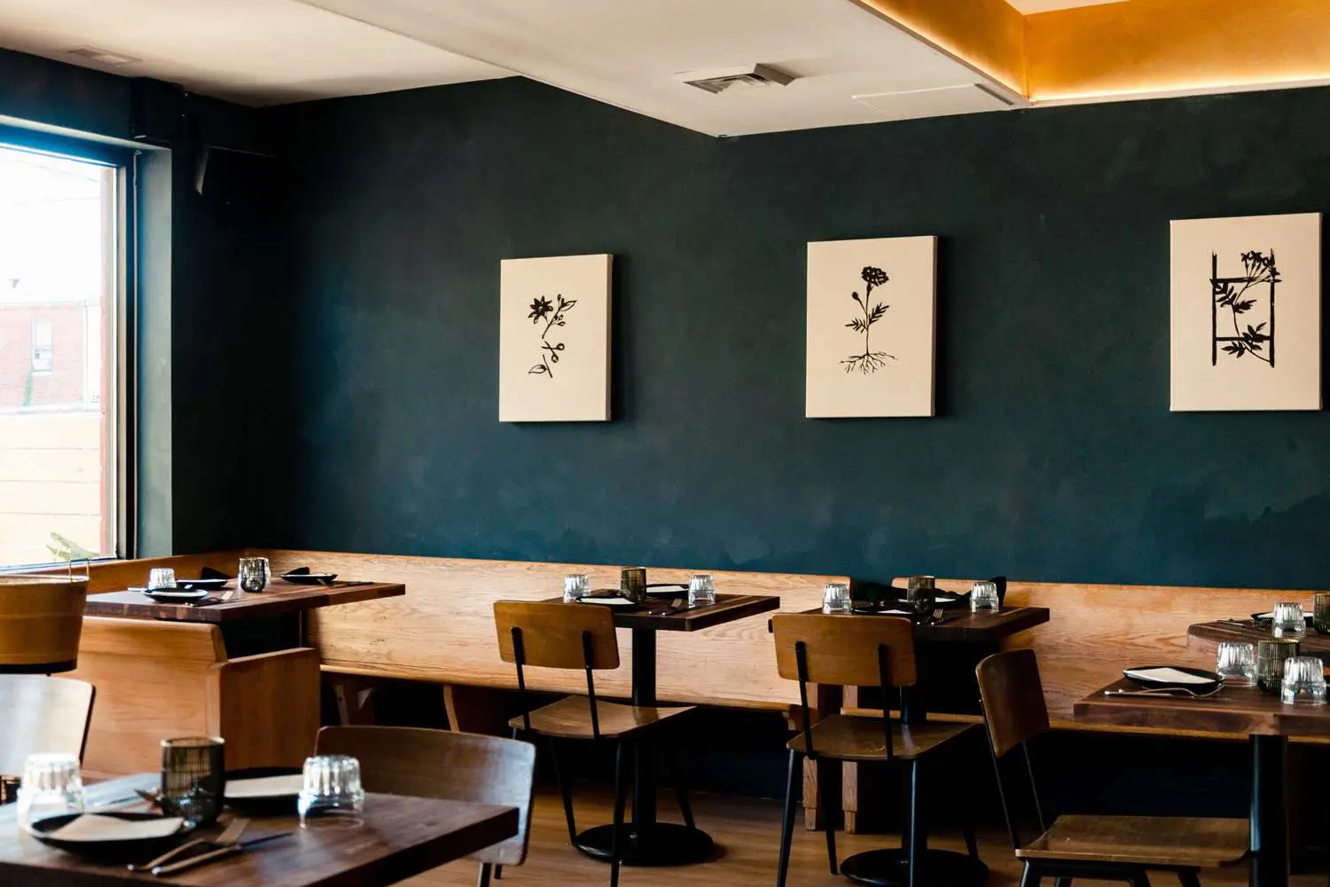 Dining room of Church with walnut pew seating, dark walls, and botanical prints inspired by world religions