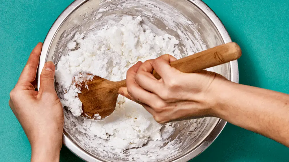 A GIF of a hand mixing a dough mixture with a spoon.