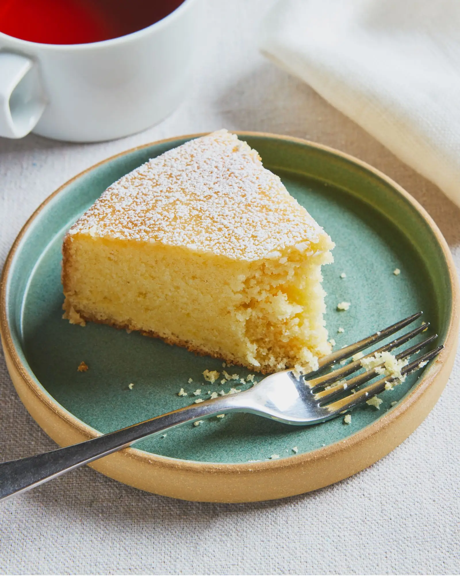 A slice of lemon cake with a bite removed.