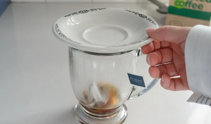 Putting a plate on the mug to retain the heat while the tea steeps.' title='Dirty Chai Latte