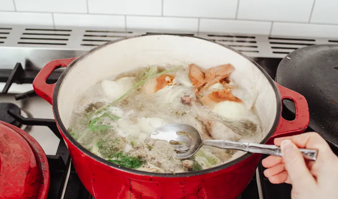 Skimming the scum off of chicken feet bone broth.' title='Chicken Feet Bone Broth Recipe