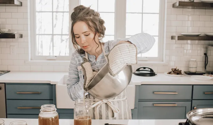 Pouring the chicken feet bone broth into glass jars for storage.' title='Chicken Feet Bone Broth Recipe