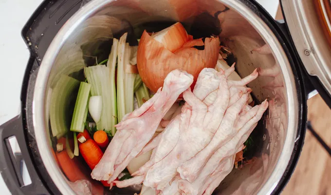 Placing ingredients for the chicken feet bone broth in the Instant Pot.' title='Chicken Feet Bone Broth Recipe