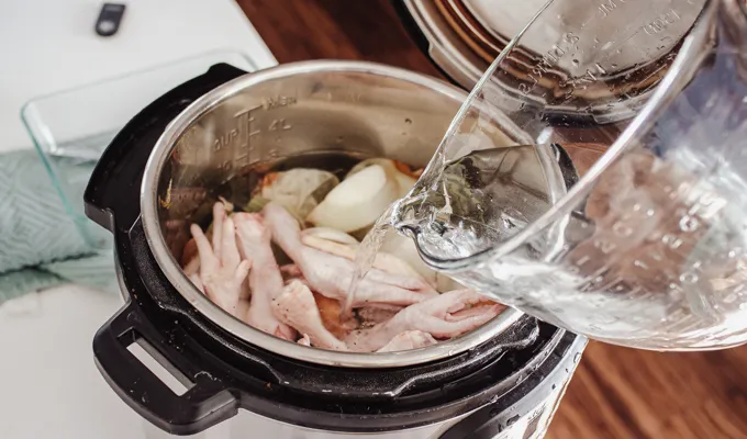 Pouring the water in for making slow cooker chicken feet bone broth.' title='Chicken Feet Bone Broth Recipe