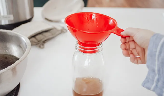 Putting a canning funnel on a jar.' title='Chicken Feet Bone Broth Recipe