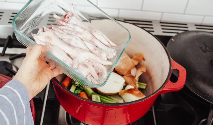 Adding chicken feet to the Dutch oven.' title='Chicken Feet Bone Broth Recipe