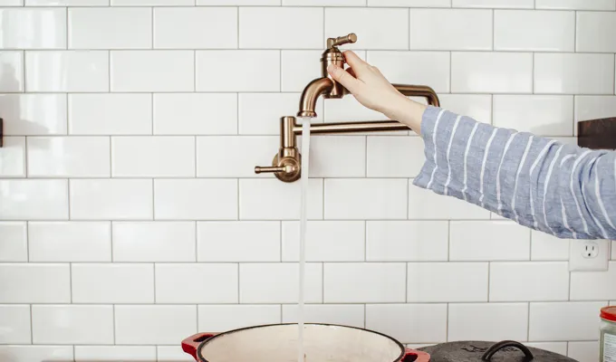 Adding water to the Dutch oven from a pot filler.' title='Chicken Feet Bone Broth Recipe