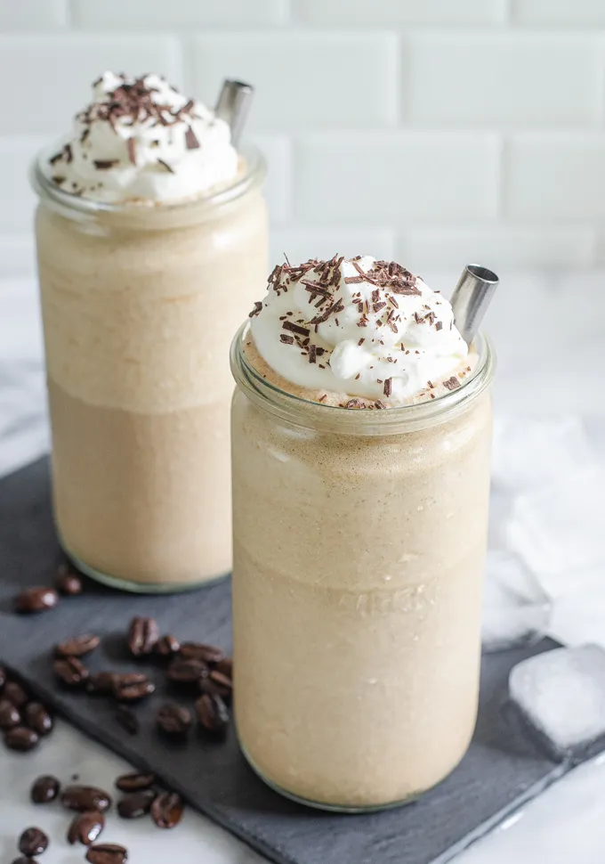 Two cups of mocha frappuccino on a slate board with coffee and ice cubes around it.' title='Mocha Frappuccino Recipe