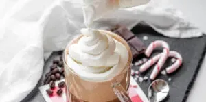 Adding whipped cream on top of the peppermint mocha.' title='Peppermint Mocha Starbucks Recipe