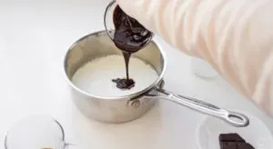 Pouring chocolate syrup into a pan of milk.' title='Peppermint Mocha Starbucks Recipe