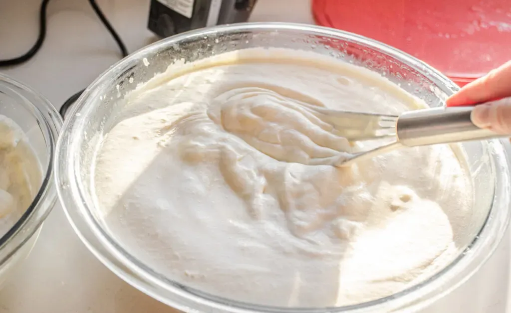 Folding the whipped cream into the custard with a wire whisk.' title='Homemade Eggnog