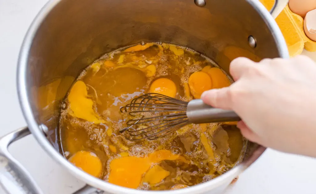 Whisking the eggs syrup and salt in a stock pot.' title='Homemade Eggnog
