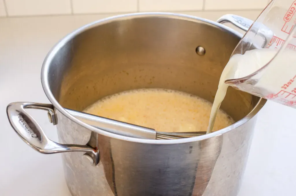 Adding half of the milk to the egg and maple syrup mixture in the pot.' title='Homemade Eggnog