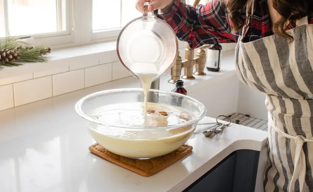 Pouring the remaining milk into the non-alcoholic eggnog custard mixture.' title='Homemade Eggnog