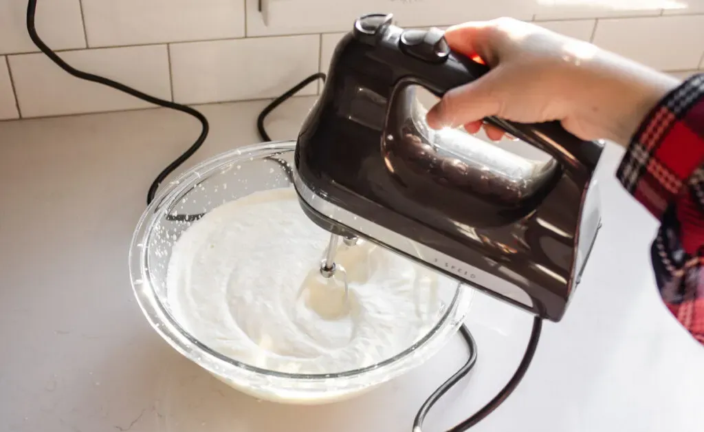 Whipping the cream until soft peaks form.' title='Homemade Eggnog