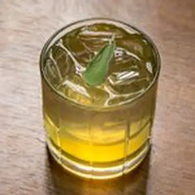 Switchel cocktail in a rocks glass garnished with a sage leaf