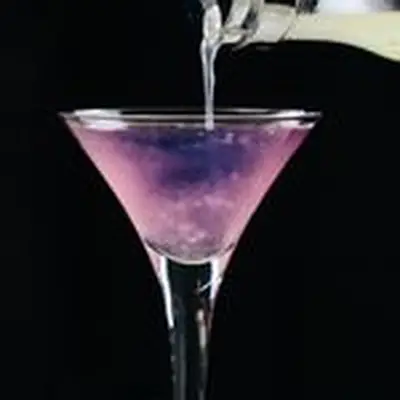 Lemon juice being poured into the Color Changing Martini, turning it from purple to pink