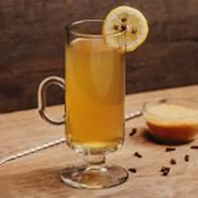 Hot Toddy cocktail in a glass mug with lemon wheel and cloves