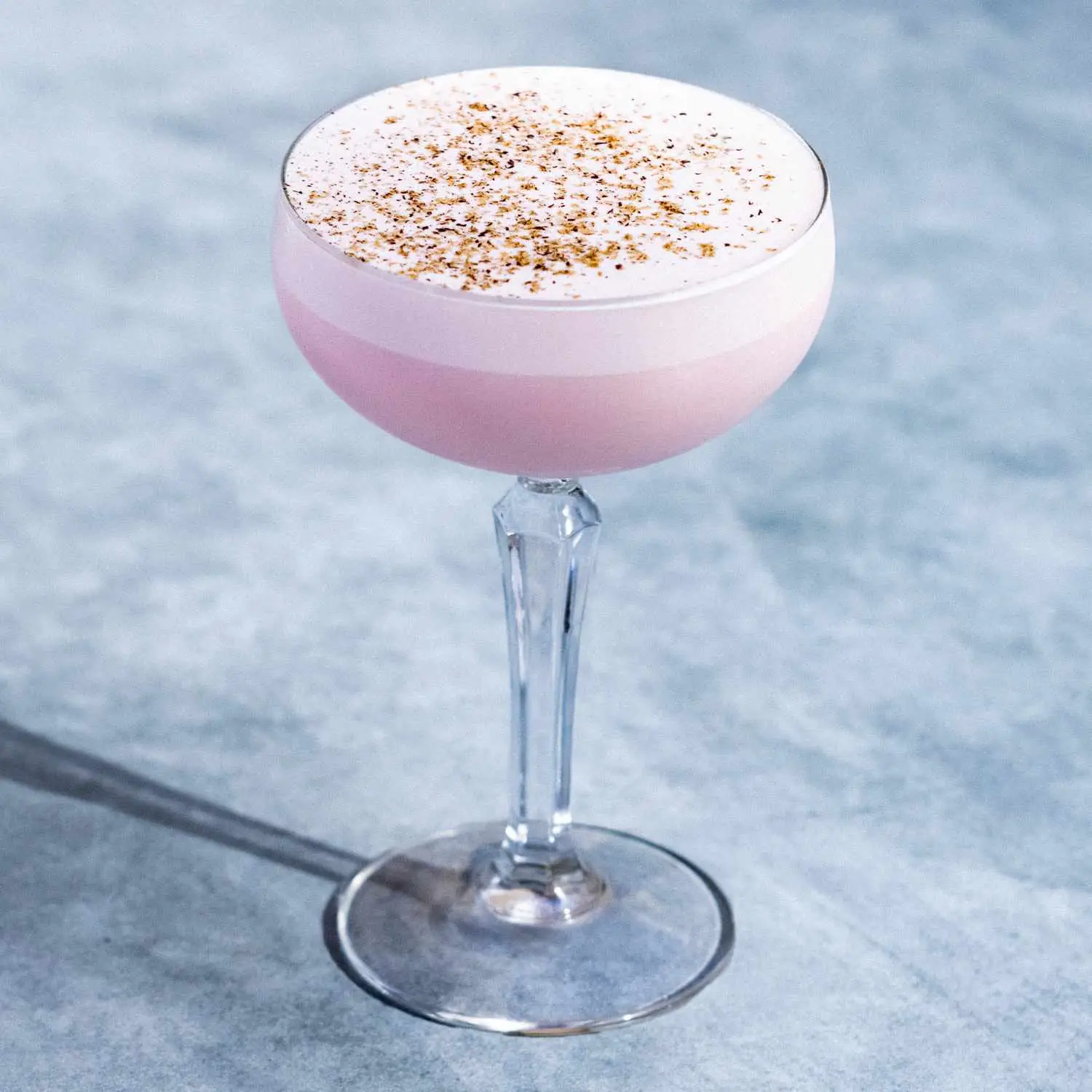 Pink Squirrel in an ornate coupe glass with lightly separate layer of pink foam and nutmeg dusting