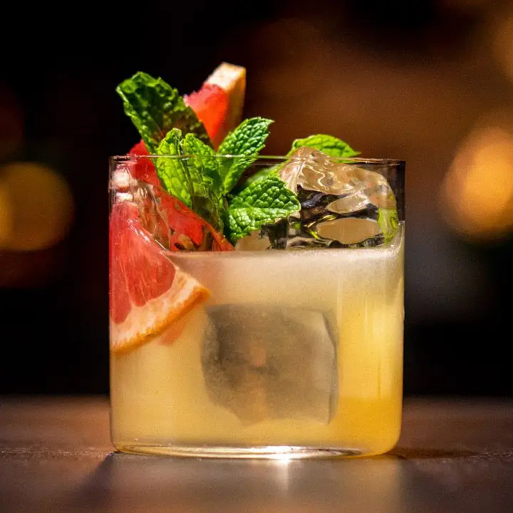 Kyoto Sour cocktail with clear ice in a thin-walled rocks glass, garnished with grapefruit wedges and mint