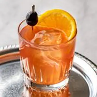 Forbidden Sour cocktail with a cherry and orange slice, served on a silver tray