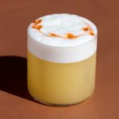 Whiskey Sour in a rocks glass with thick foam of egg white on top, dotted with swirls of Angostura bitters