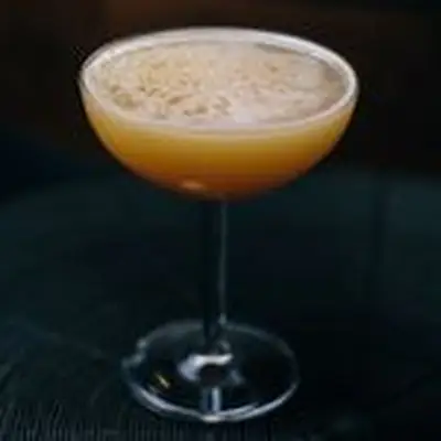 Chicken & Apple Wassail cocktail in a coupe glass on a black surface