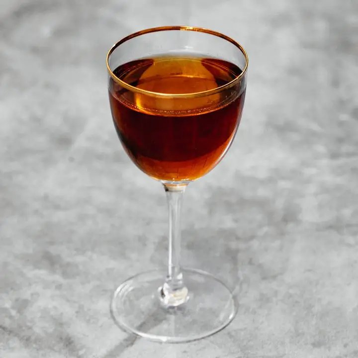 Bijou cocktail in gold rimmed coupe glass, shot on gray marble 