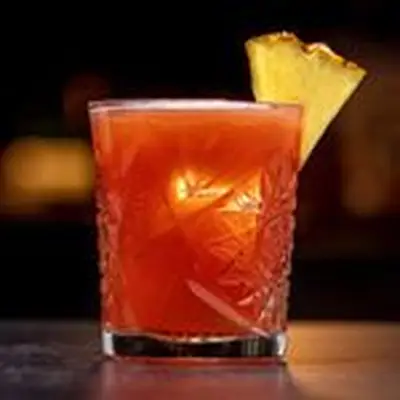 Jungle Bird cocktail in crystal-cut rocks glass with pineapple wedge garnish